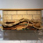 An artwork about inequality made in beige and brown colours, embroidered bricks and tree roots made of ropes